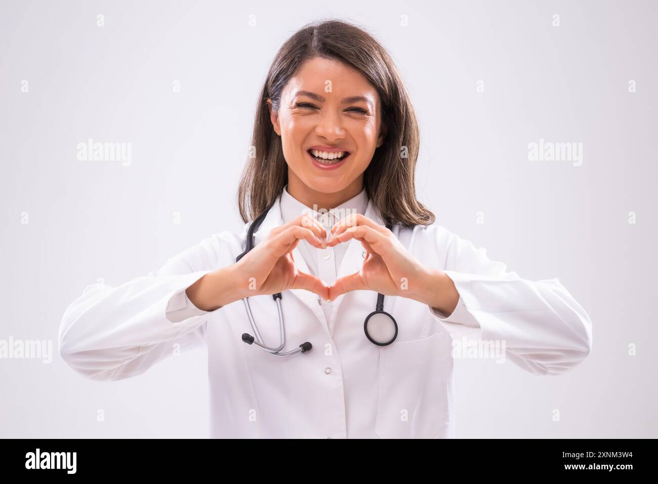 Ritratto di un medico allegro che mostra la forma del cuore con le mani. Foto Stock