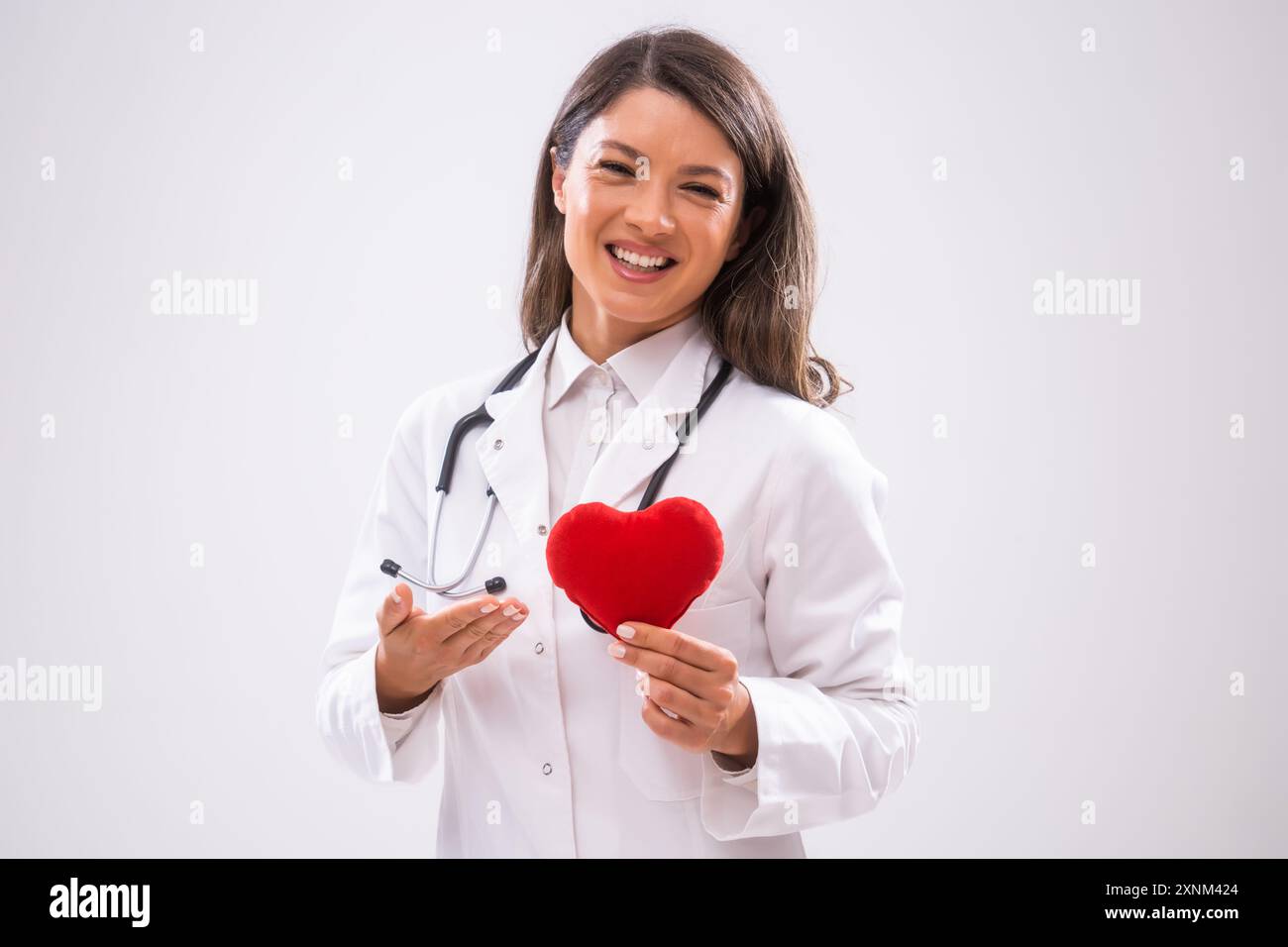 Ritratto di un medico felice che mostra un cuscino a forma di cuore. Foto Stock