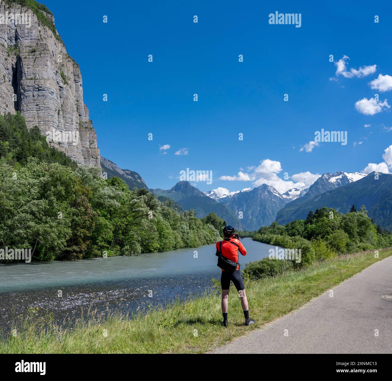 Il ciclista su strada maschile si ferma per scattare una foto del percorso ciclistico verde tra Allemond e Bourg d'Oisans, Valle Romanche, Alpi francesi. Foto Stock