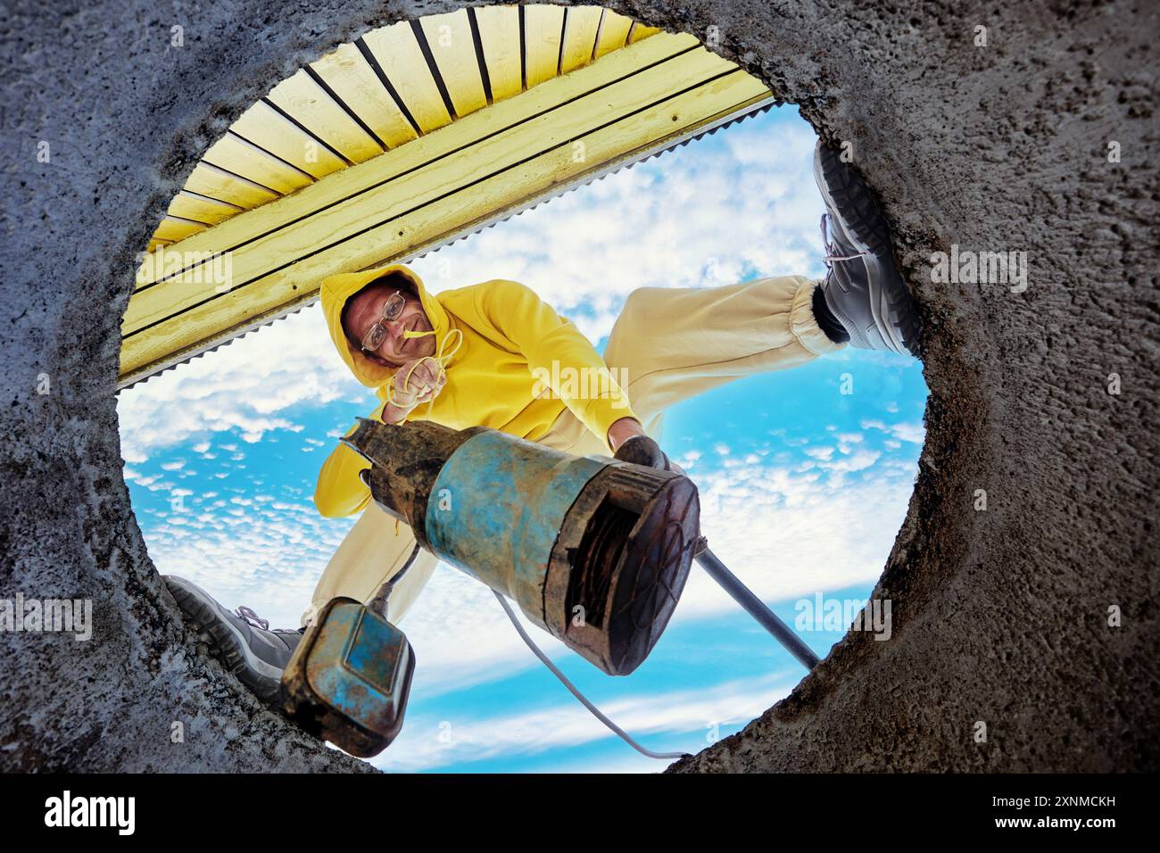 Vista dal basso dell'uomo che immerge la pompa delle acque reflue nelle acque reflue del serbatoio settico. Foto Stock