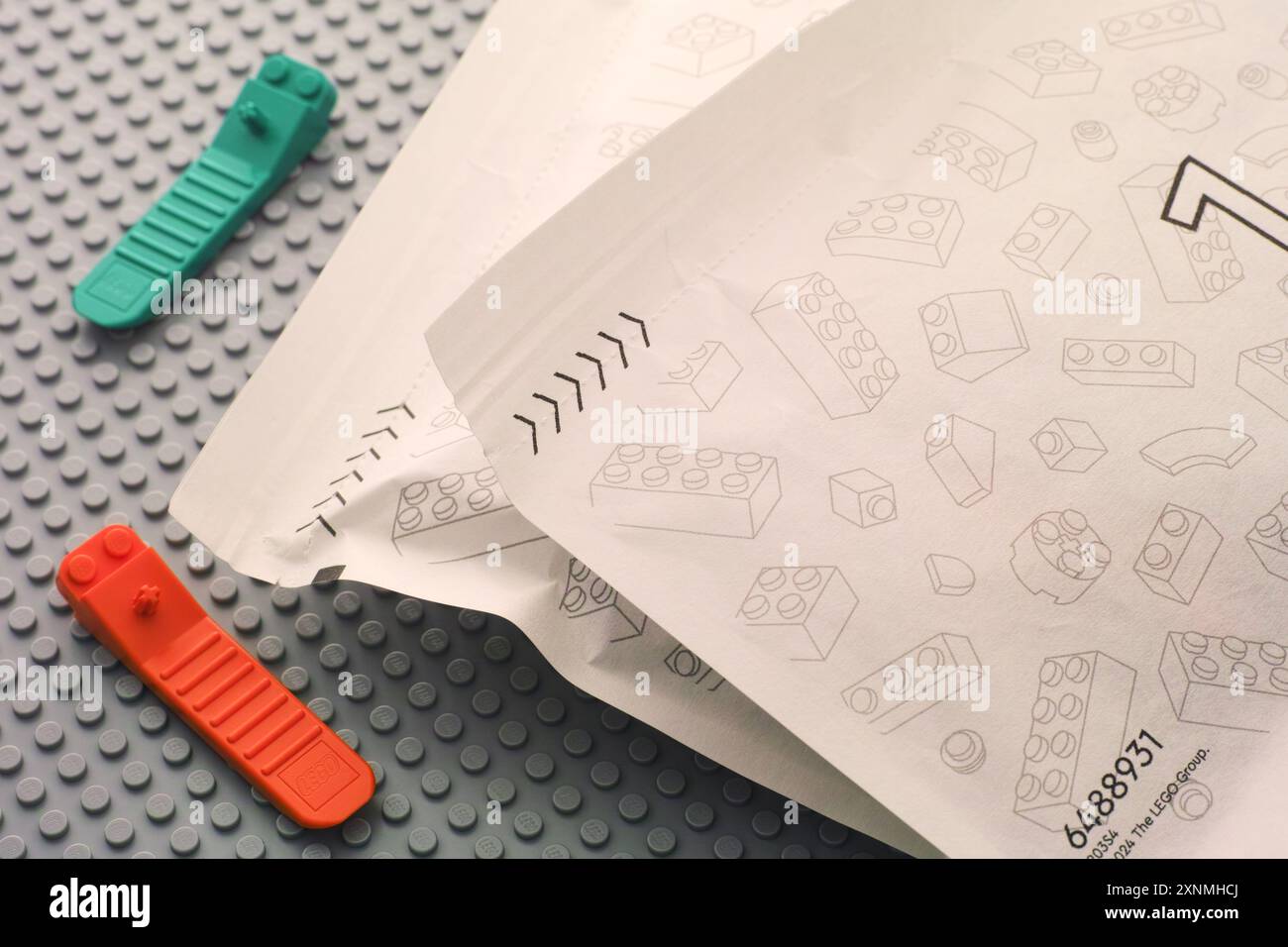 Tambov, Federazione Russa - 22 giugno 2024 due separatori in mattoni Lego e due sacchetti di carta con pezzi Lego su una piastra di base grigia Foto Stock