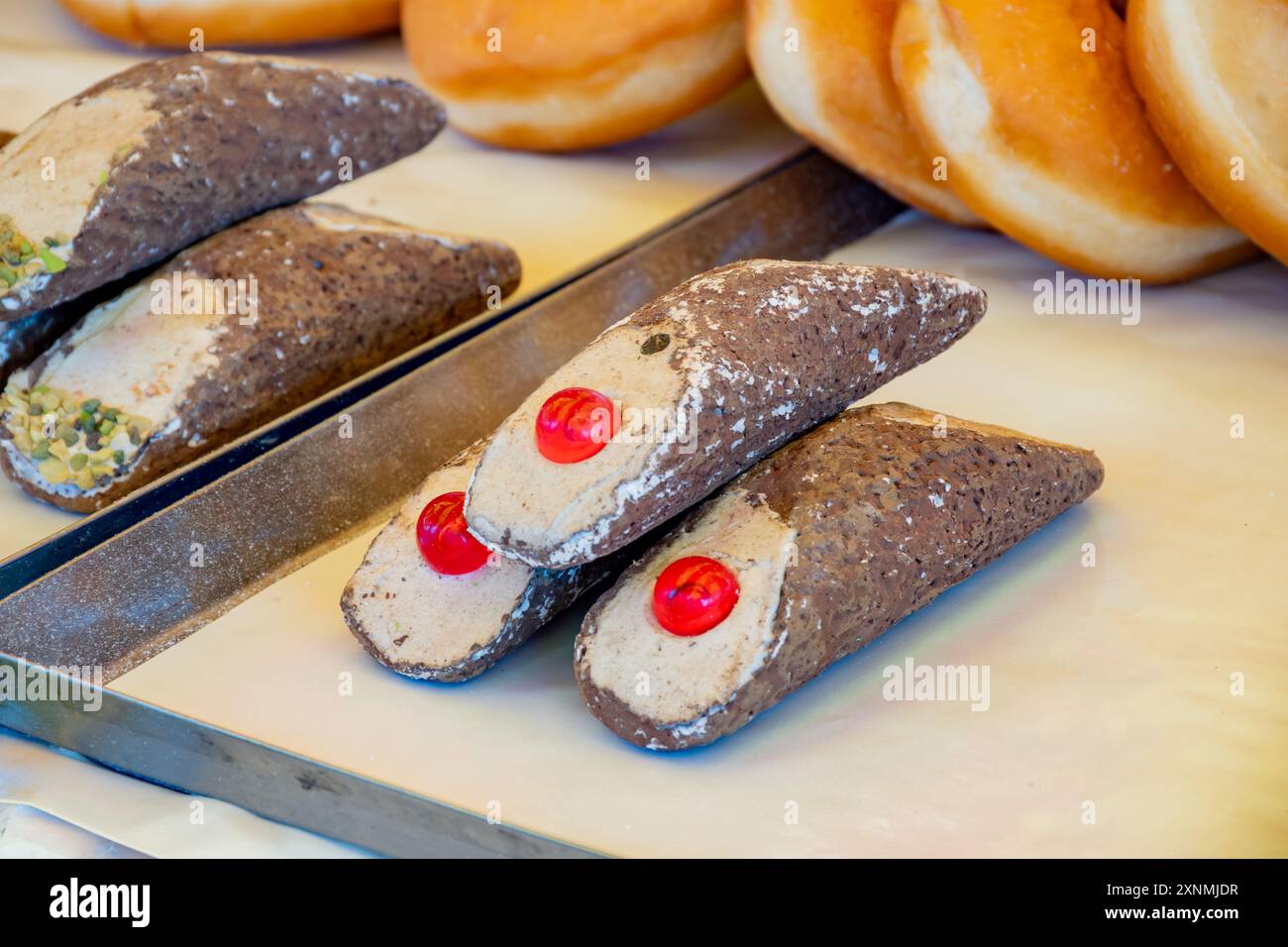 Cannolo siciiano di pasta dolce fatta in casa ripieno di mandorle, pistacchio, limone, vaniglia, crema al cioccolato sul mercato alimentare italiano Foto Stock