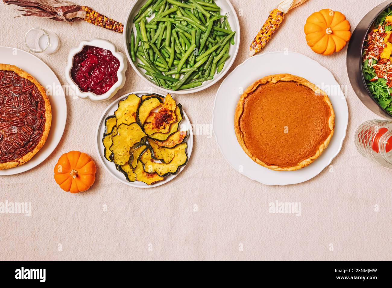 Un tavolo del Ringraziamento ben organizzato con torta di zucca fatta in casa, fagioli verdi vivaci, zucca arrosto e insalata fresca. Foto Stock
