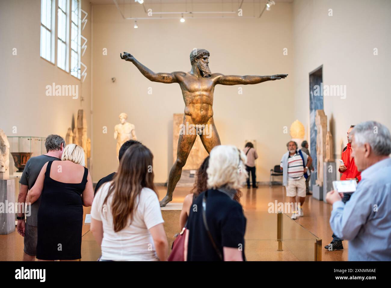 Zeus o statua in bronzo di Poseidone Museo Archeologico Nazionale Atene // ATENE, Grecia — la statua di Zeus o Poseidone, una suggestiva scultura in bronzo del V secolo a.C., è una delle più famose mostre al Museo Archeologico Nazionale di Atene. Si ritiene che questa iconica scultura, scoperta nel mare al largo di Capo Artemision, rappresenti Zeus, che regge un fulmine, o Poseidone, che brandisce un tridente. La statua è celebrata per la sua posa dinamica e l'intricata maestria artigianale, che esemplifica l'eccellenza artistica degli antichi scultori greci. Foto Stock