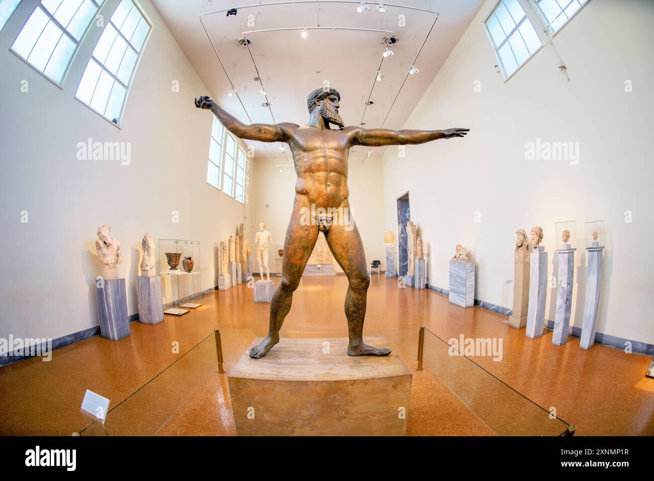 Zeus o statua di Poseidone Museo Archeologico Nazionale Atene // ATENE, Grecia — la statua di Zeus o Poseidone, una suggestiva scultura in bronzo del V secolo a.C., è una delle più famose mostre al Museo Archeologico Nazionale di Atene. Si ritiene che questa iconica scultura, scoperta nel mare al largo di Capo Artemision, rappresenti Zeus, che regge un fulmine, o Poseidone, che brandisce un tridente. La statua è celebrata per la sua posa dinamica e l'intricata maestria artigianale, che esemplifica l'eccellenza artistica degli antichi scultori greci. Foto Stock