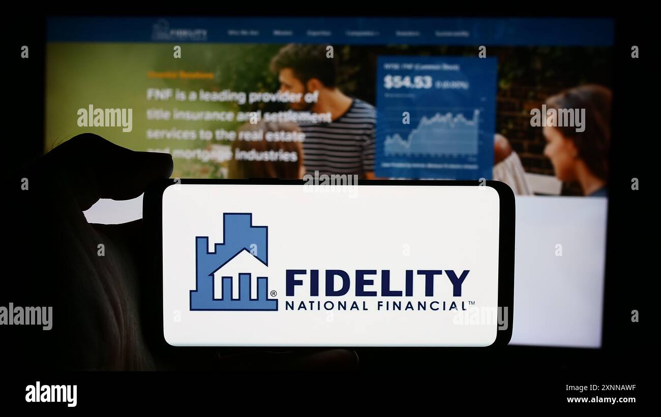 Persona che detiene un cellulare con il logo della società finanziaria statunitense Fidelity National Financial Inc. Di fronte alla pagina Web aziendale. Mettere a fuoco il display del telefono. Foto Stock