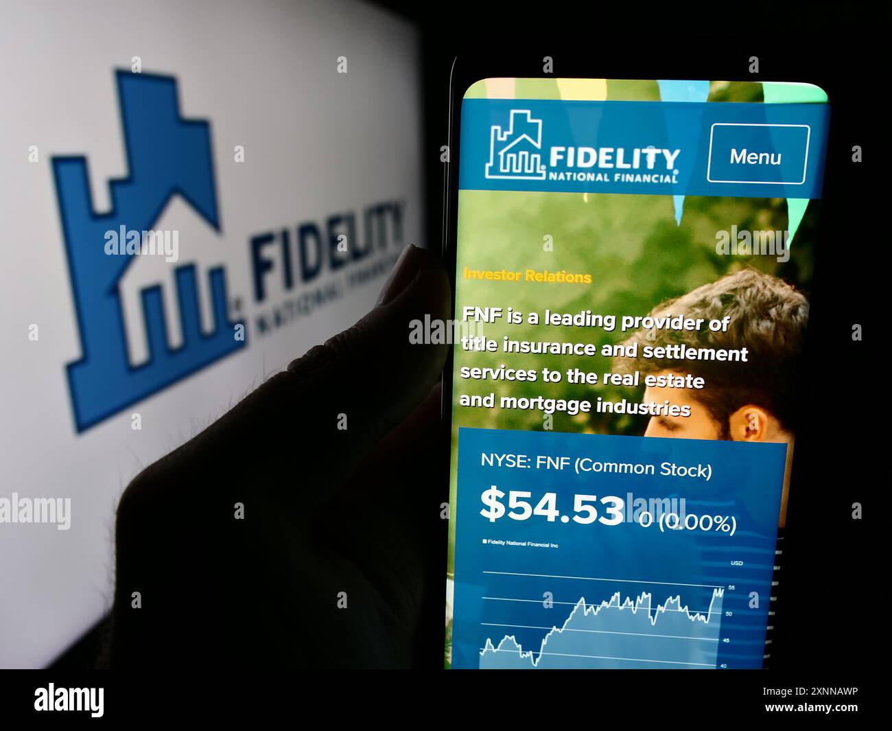 Persona che detiene lo smartphone con il sito Web della società finanziaria statunitense Fidelity National Financial Inc. Con il logo. Messa a fuoco al centro del display del telefono. Foto Stock
