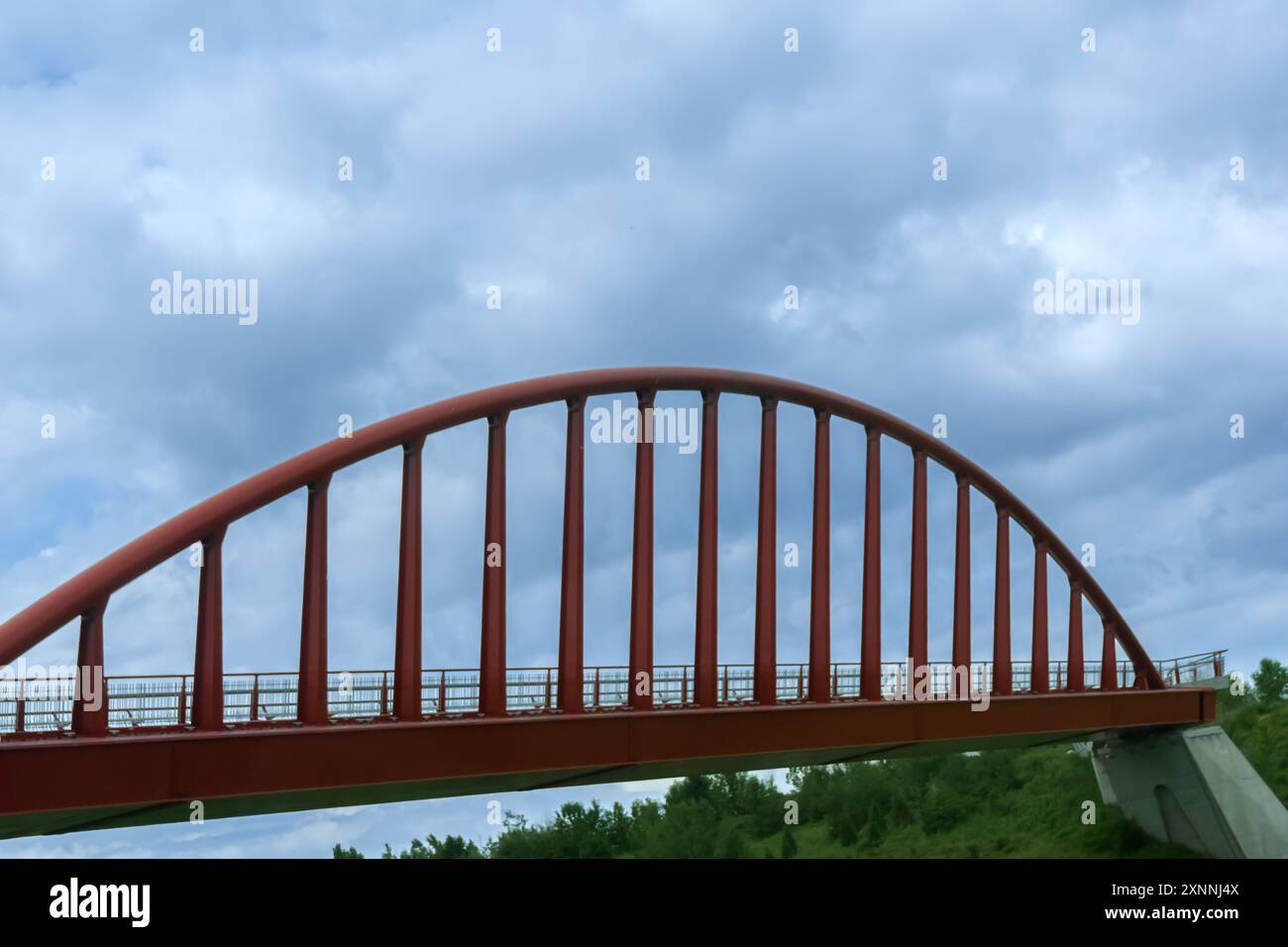 Semplice ponte pedonale con telaio curvo rosso che attraversa un burrone Foto Stock