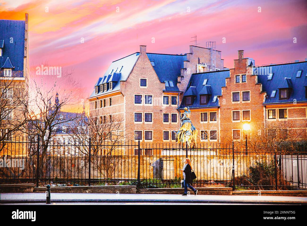 Bruxelles, Belgio, 17 marzo 2020: Paesaggio urbano della sera Bruxelles al tramonto. Una persona passeggia davanti a un complesso di edifici storici sotto un vivace e colorato Foto Stock