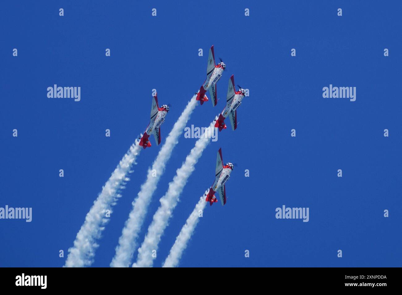 Symbolbild Kunstflugshow, vier Flugzeuge, formazione, Kondensstreifen, blauer Himmel, präzises Fliegen, rote und weiße Lackierung, beeindruckende Flugmanöver, Luftakrobatik, aufregendes Spektakel, Flugshow, lavoro di squadra, Luftfahrtenthusiasten, Flugkünste, Dyische Vorführung, hoher Schwierigkeitsgrad, öffentliche Veranstaltung, Freizeitaktivität, Pilotenfähigkeiten, Aeroshell *** spettacolo acrobatico con immagini simboliche, quattro aerei, formazione, contraglie, cielo blu, volo preciso, livrea rossa e bianca, impressionanti manovre di volo, acrobazie aeree, spettacolo emozionante, spettacolo aereo, lavoro di squadra, aviazione enthus Foto Stock