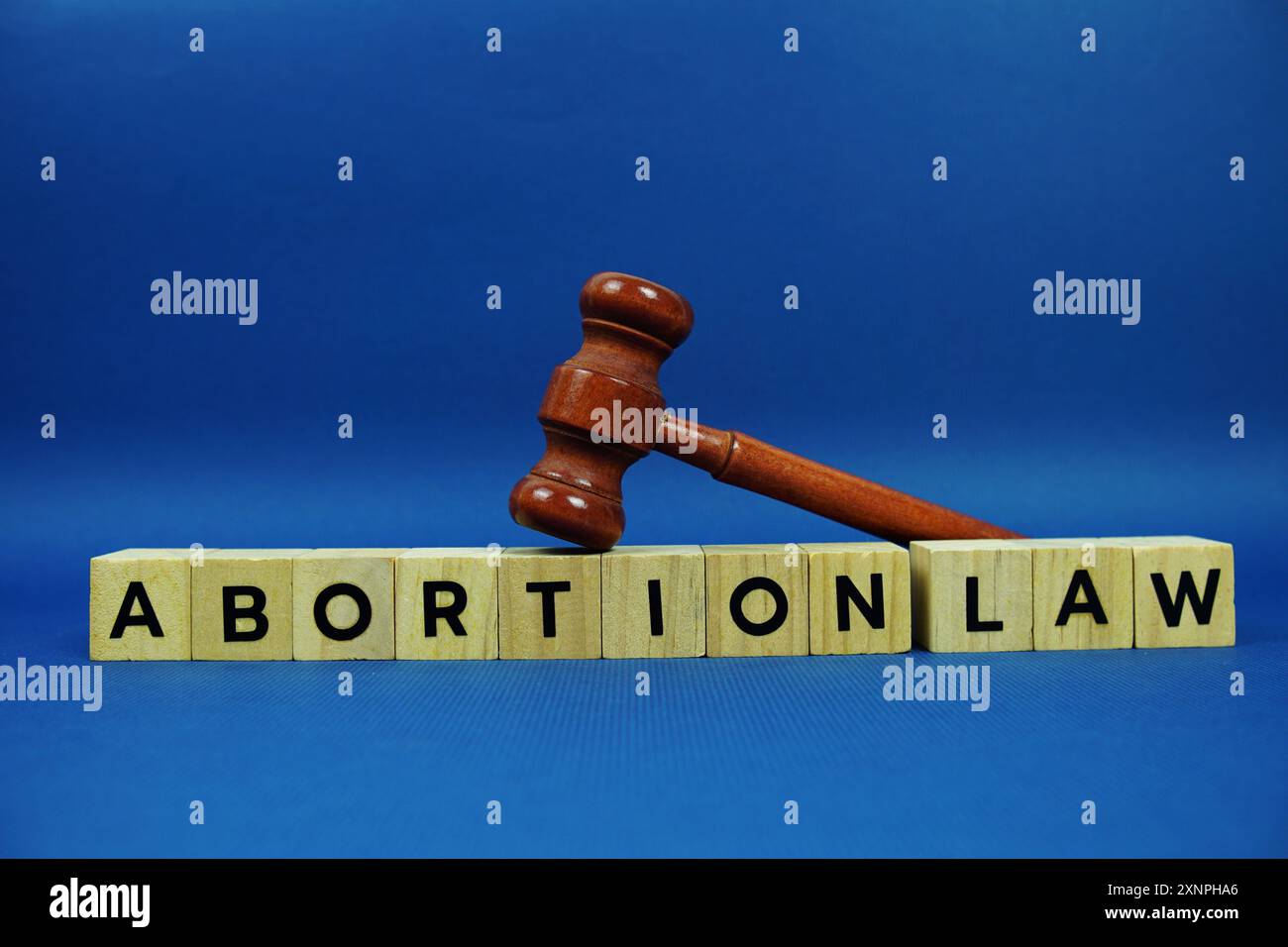 Lettere dell'alfabeto della legge sull'aborto con blocchi di legno lettere dell'alfabeto e martelletto su sfondo blu Foto Stock