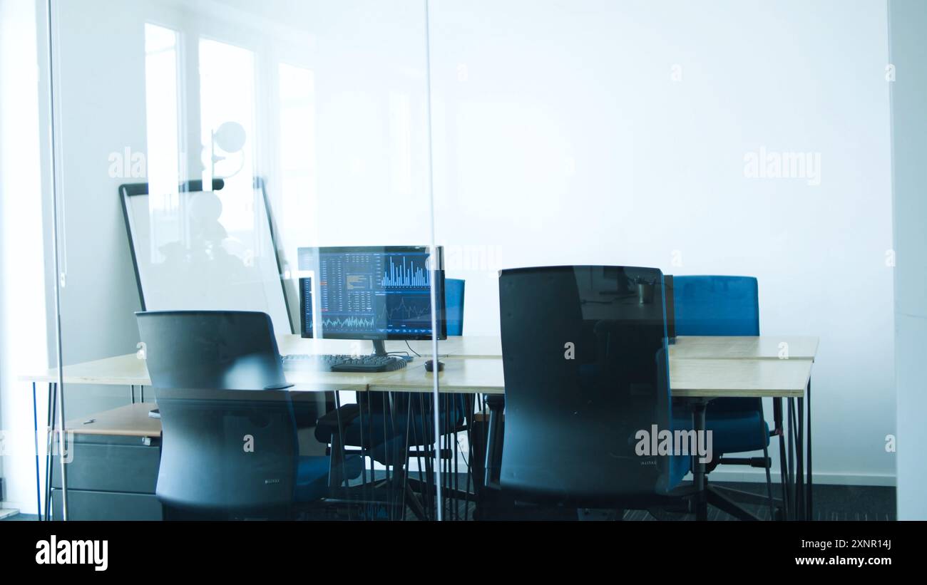 Ufficio moderno dal design pulito e organizzato. Il luogo di lavoro è dotato di file di scrivanie individuali dotate di computer e comode sedie da ufficio Foto Stock