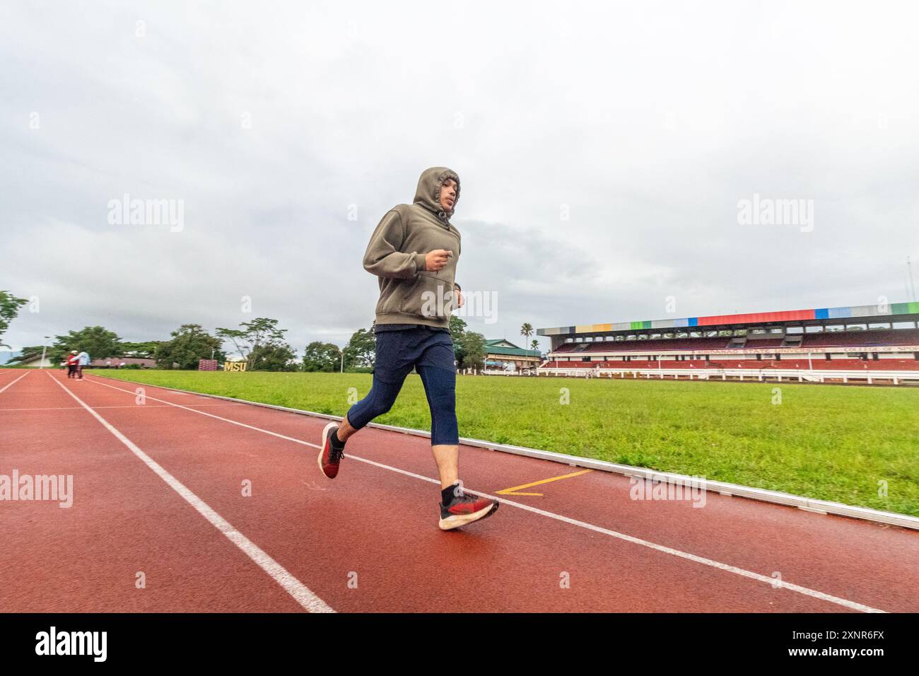 Un jogger filippino in una felpa con cappuccio che corre sulla pista ovale di Marawi City, Filippine Foto Stock