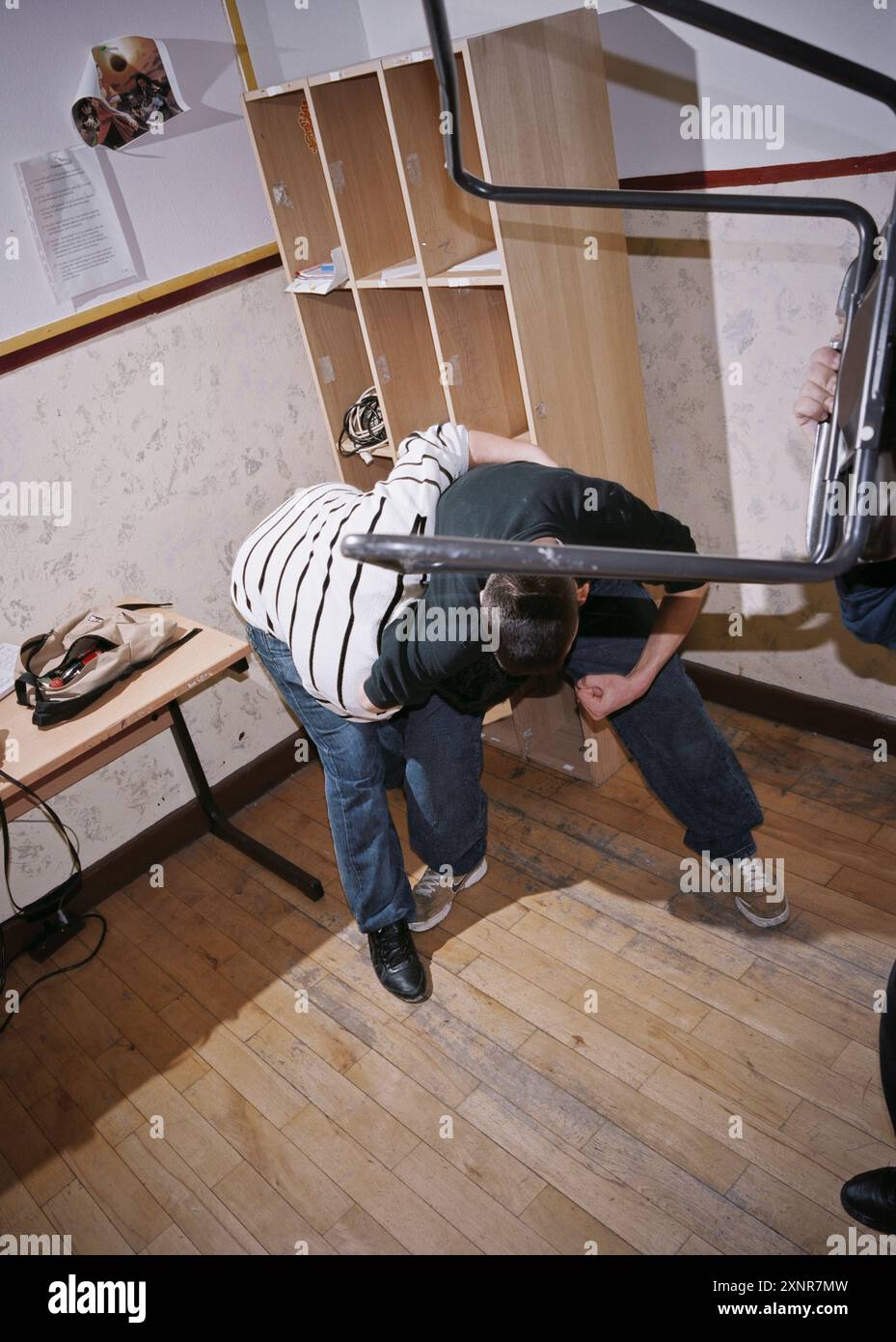 Scena intensa di studenti delle scuole superiori impegnati in una lotta fisica all'interno di una classe. Raffigura il caos e la violenza che possono verificarsi in ambito educativo Foto Stock