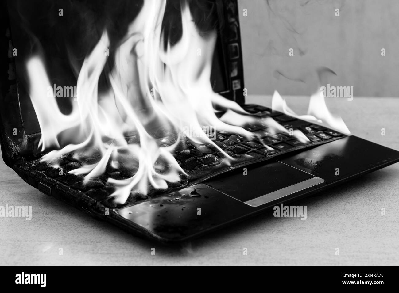 Un laptop aperto brucia in una foto in bianco e nero Foto Stock