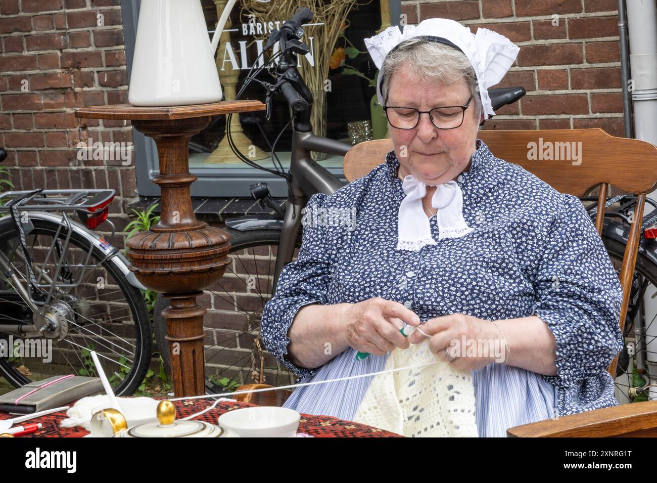 Barneveld, Paesi Bassi - 1° agosto 2024: Donna in abiti contadini che mostra maglieria al tradizionale mercato Veluwe di Barneveld nella provincia di Gelderland nei Paesi Bassi Foto Stock