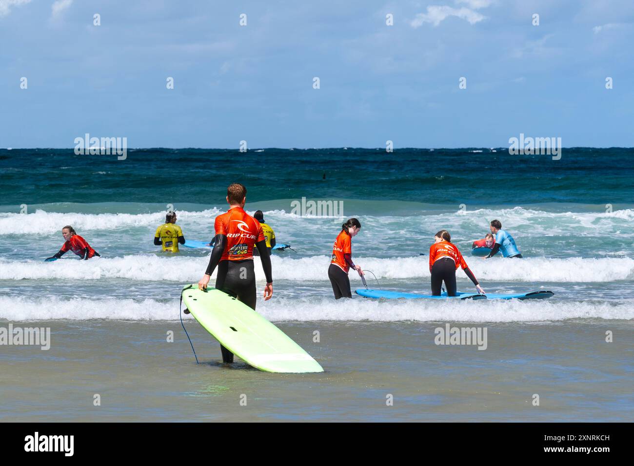 Principianti di surf che tengono una lezione di surf con istruttori del NQY Activity Centre di Towan Beach a Newquay in Cornovaglia nel Regno Unito. Foto Stock