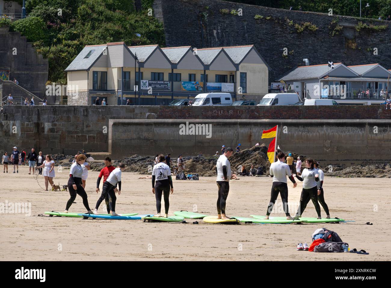 Un gruppo di principianti di surf che si preparano per una lezione di surf con un istruttore della scuola di surf SSS a Towan Beach a Newquay in Cor Foto Stock