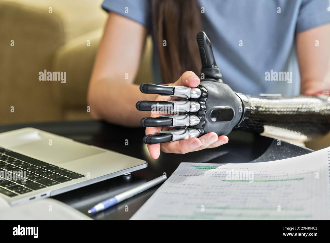 Una giovane donna con protesi e cuffie sembra un libro da lavoro e un notebook Foto Stock