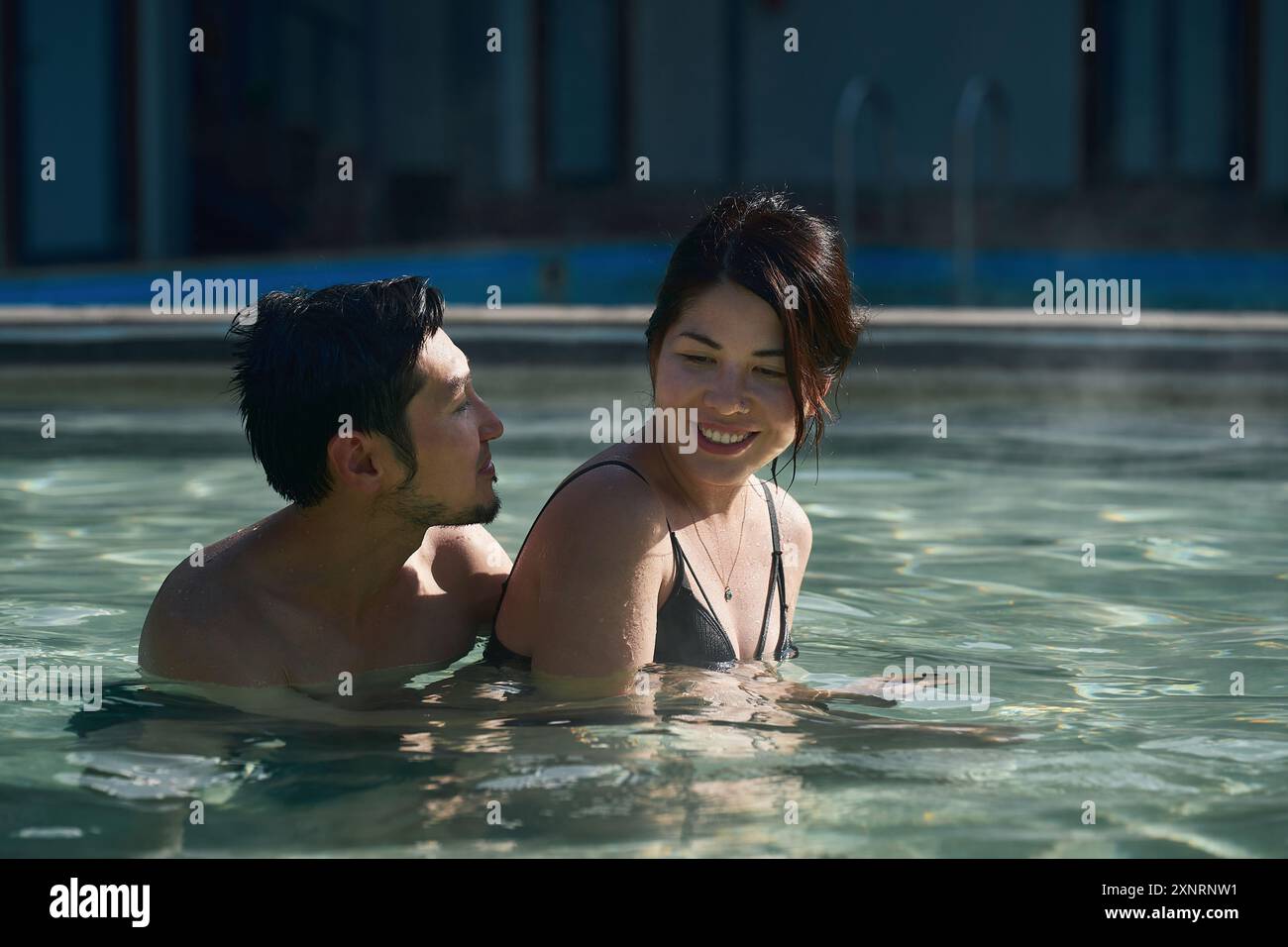 Una giovane coppia asiatica si diverte a nuotare in una piscina termale calda Foto Stock