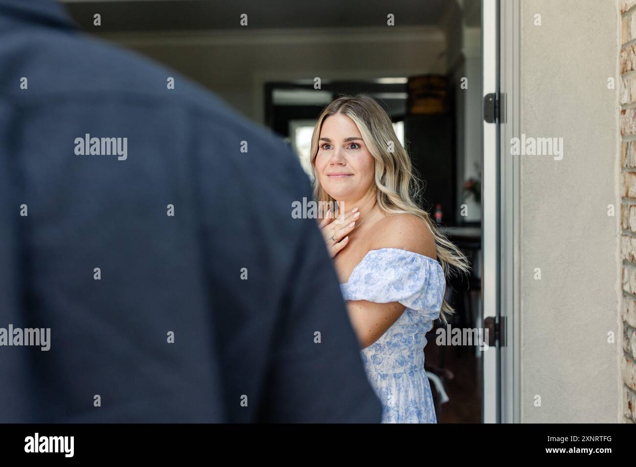 Donna in abito blu, mano sul petto, che sembra emotiva Foto Stock