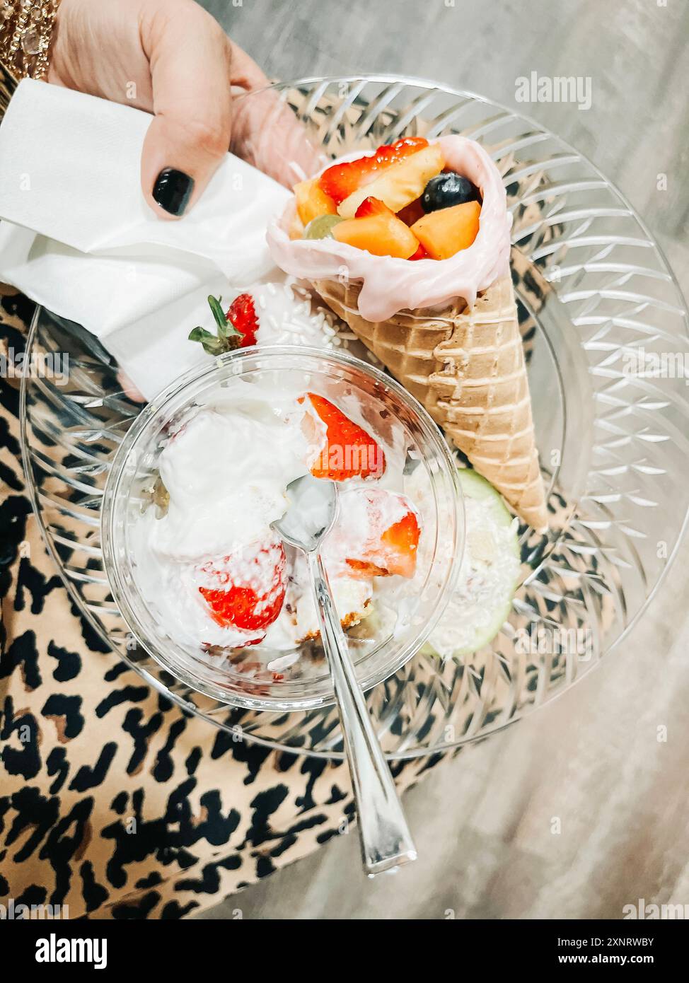 Tenere a mano un piatto con un cono di frutta e un parfa di yogurt Foto Stock