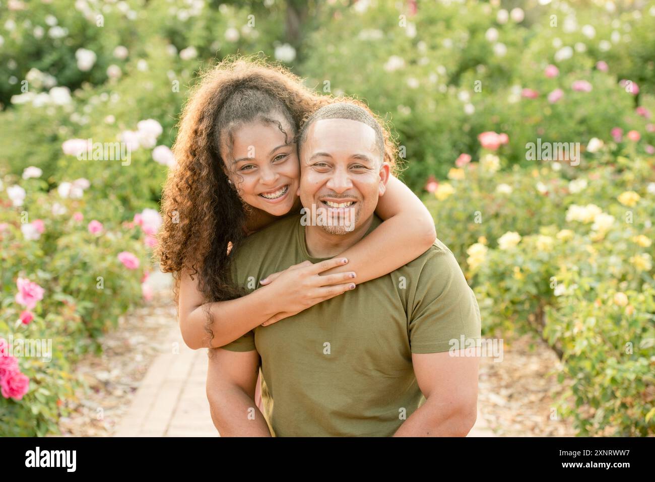 Figlia che abbraccia il padre in giardino Foto Stock