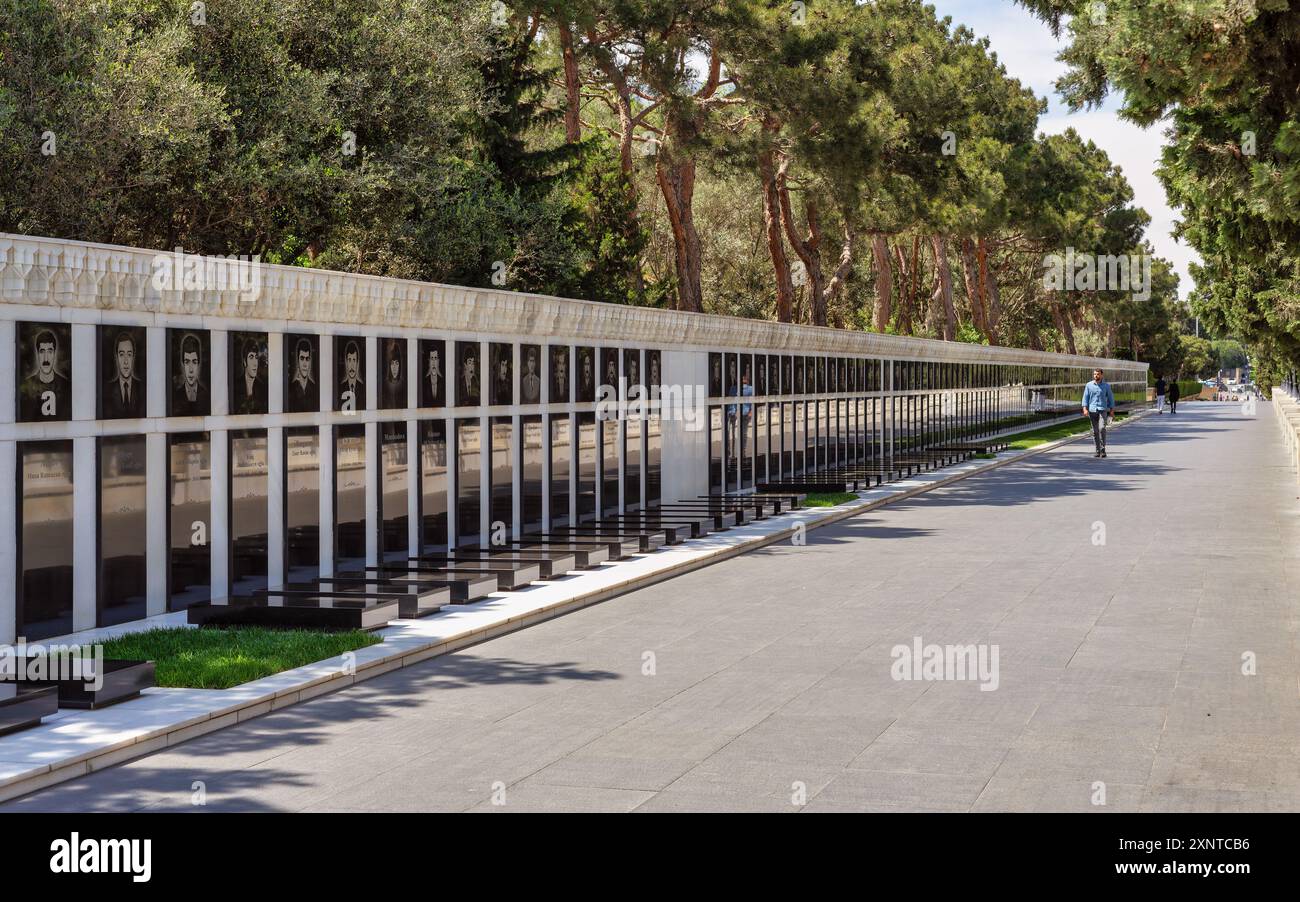 Baku, Azerbaigian - 6 maggio 2024: Pochi visitatori passeggiano lungo il vicolo dei Martiri, osservando ritratti commemorativi tra alberi verdeggianti e un'atmosfera serena Foto Stock