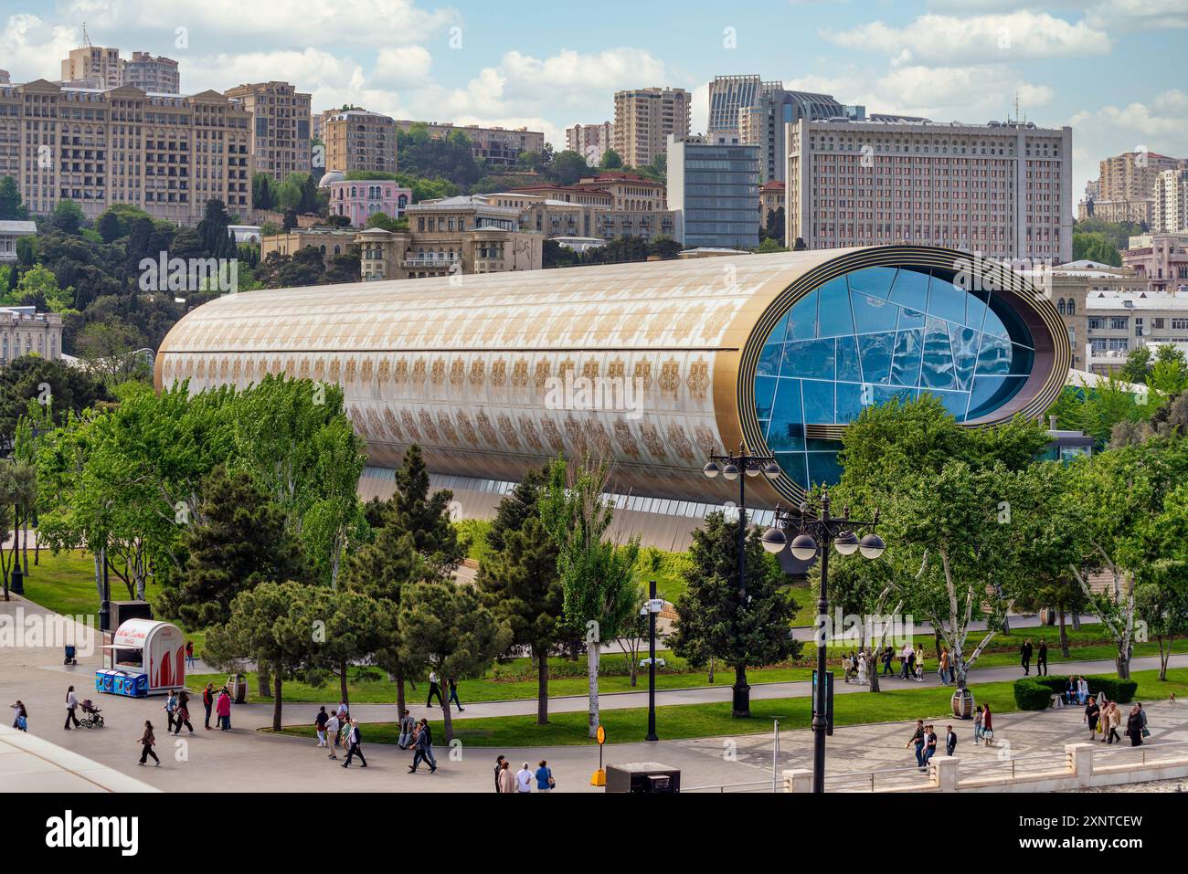Baku, Azerbaigian - 5 maggio 2024: I visitatori esplorano l'architettura unica e le mostre del Museo dei tappeti di Baku, circondato dal verde e dalla vita cittadina. Foto Stock