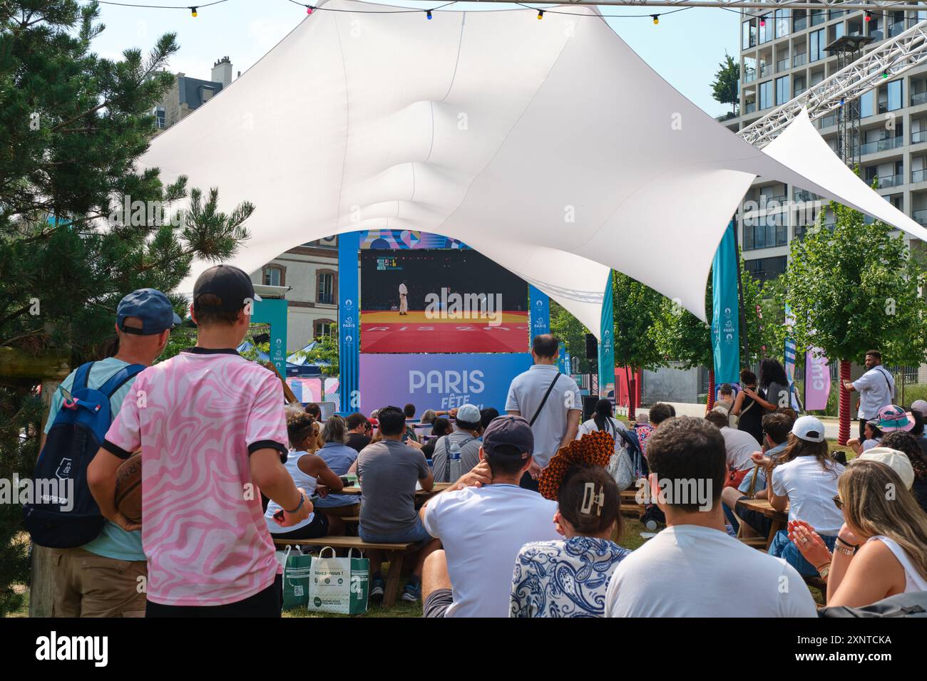 Zona dei tifosi delle Olimpiadi di Parigi 2024 nel parco Clichy Batignolles Martin Luther-King (17° arrondissement). Persone che guardano le Olimpiadi estive su un grande schermo Foto Stock