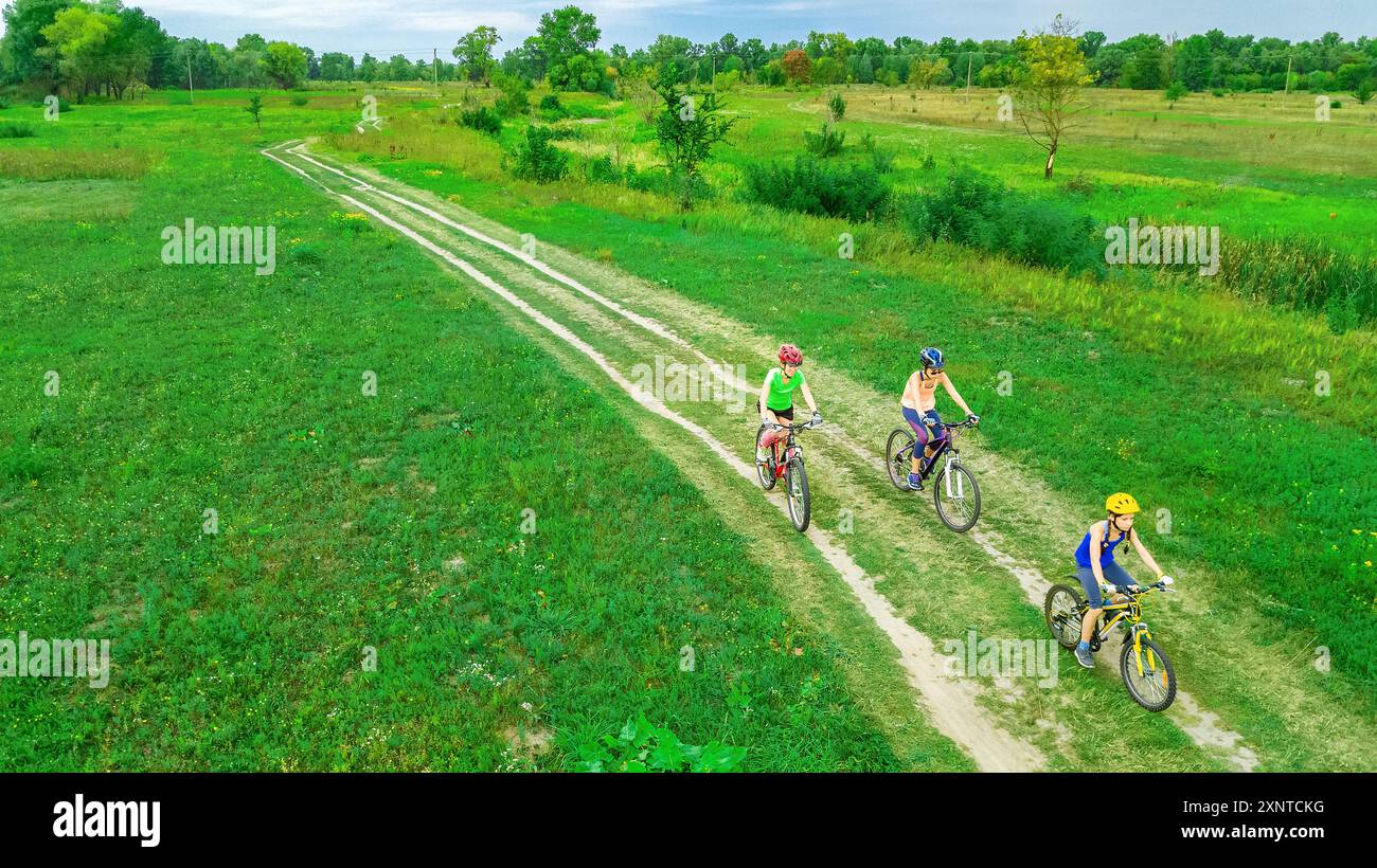 La famiglia va in bicicletta all'aperto vista dall'alto, madre felice e attiva con i bambini si diverte, sport per tutta la famiglia e fitness Foto Stock