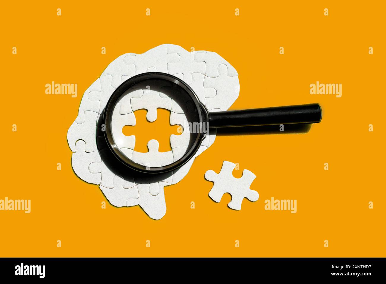 Cervello fatto di pezzi bianchi del puzzle, con una lente d'ingrandimento che si concentra su un pezzo vuoto del puzzle isolato su sfondo giallo. Salute mentale, cognizione, AN Foto Stock