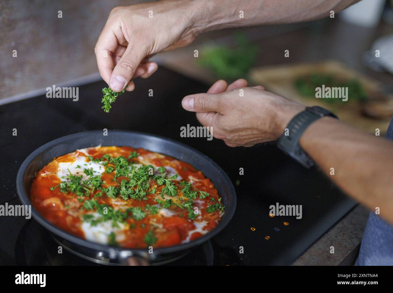 Thema kochen. Ein Mann wuerzt Essen mit Petersilie. Berlino, 01.08.2024. Berlin Deutschland *** tema cucina Un uomo stagioni cibo con prezzemolo Berlino, 0 Foto Stock