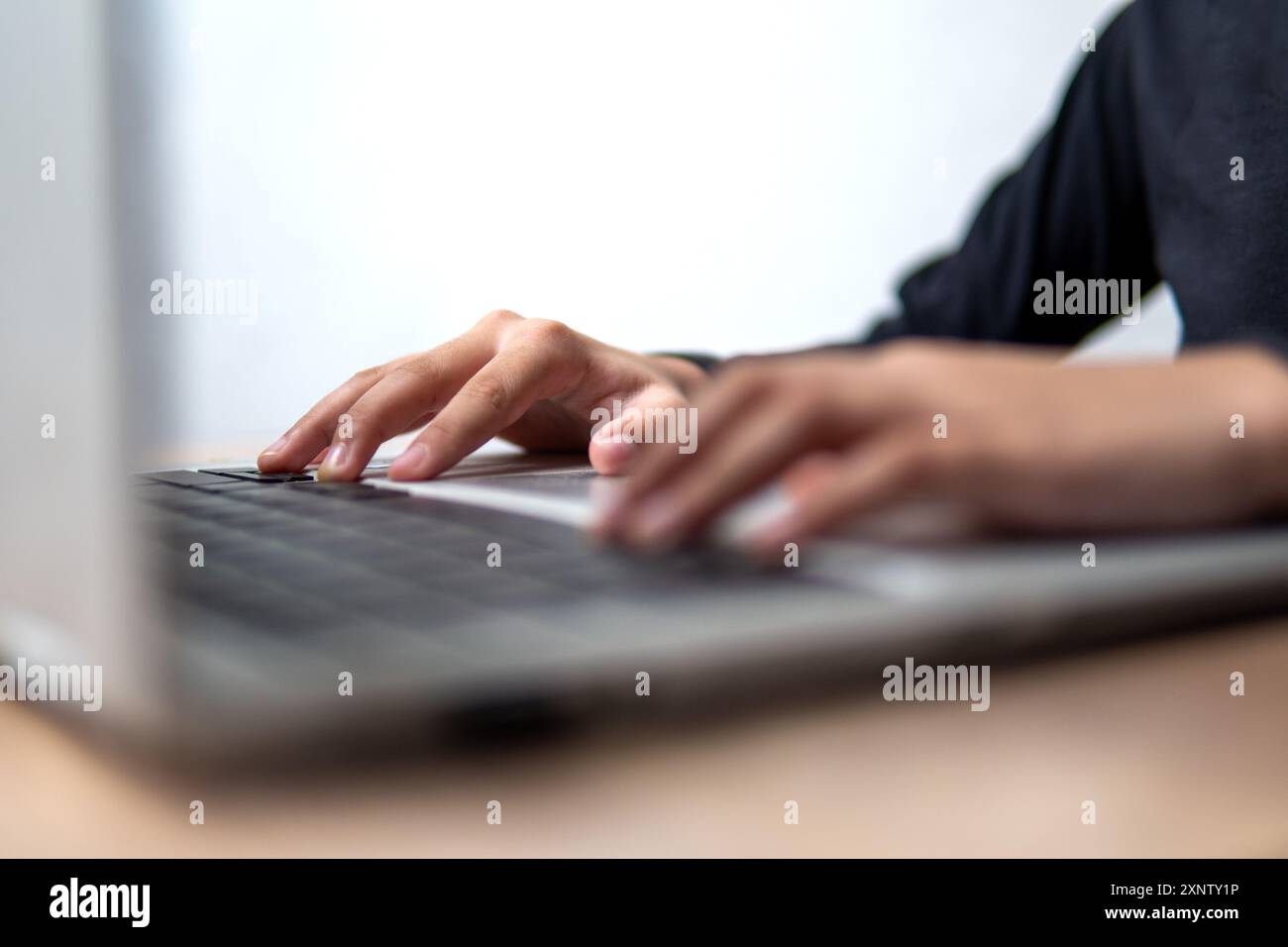 Immagine ravvicinata delle mani di una persona che digita sulla tastiera di un notebook. Foto Stock