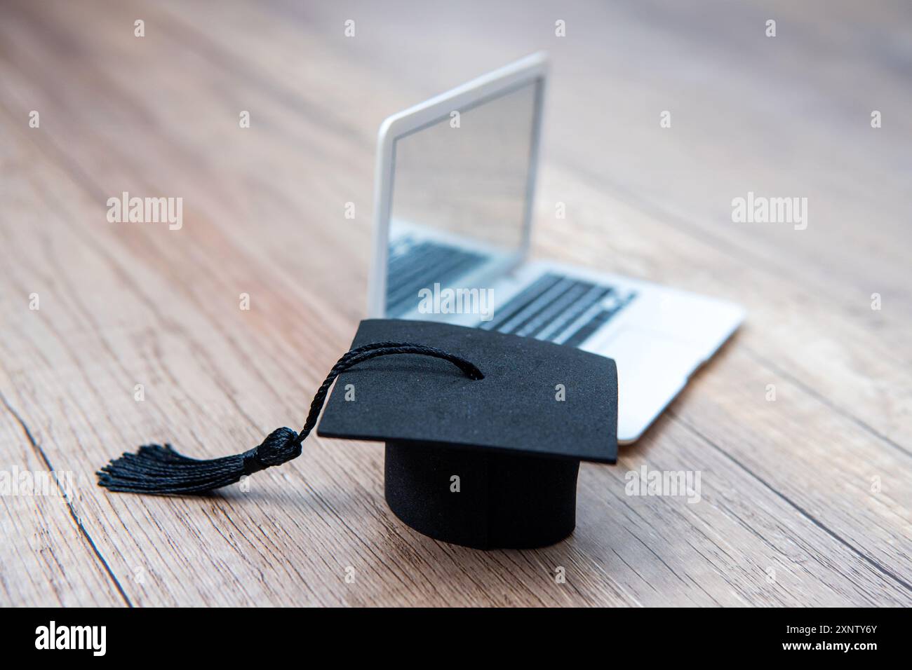 Un berretto graduato e un notebook. Copia spazio per il testo. Apprendimento online e concetto di risultati accademici. Foto Stock
