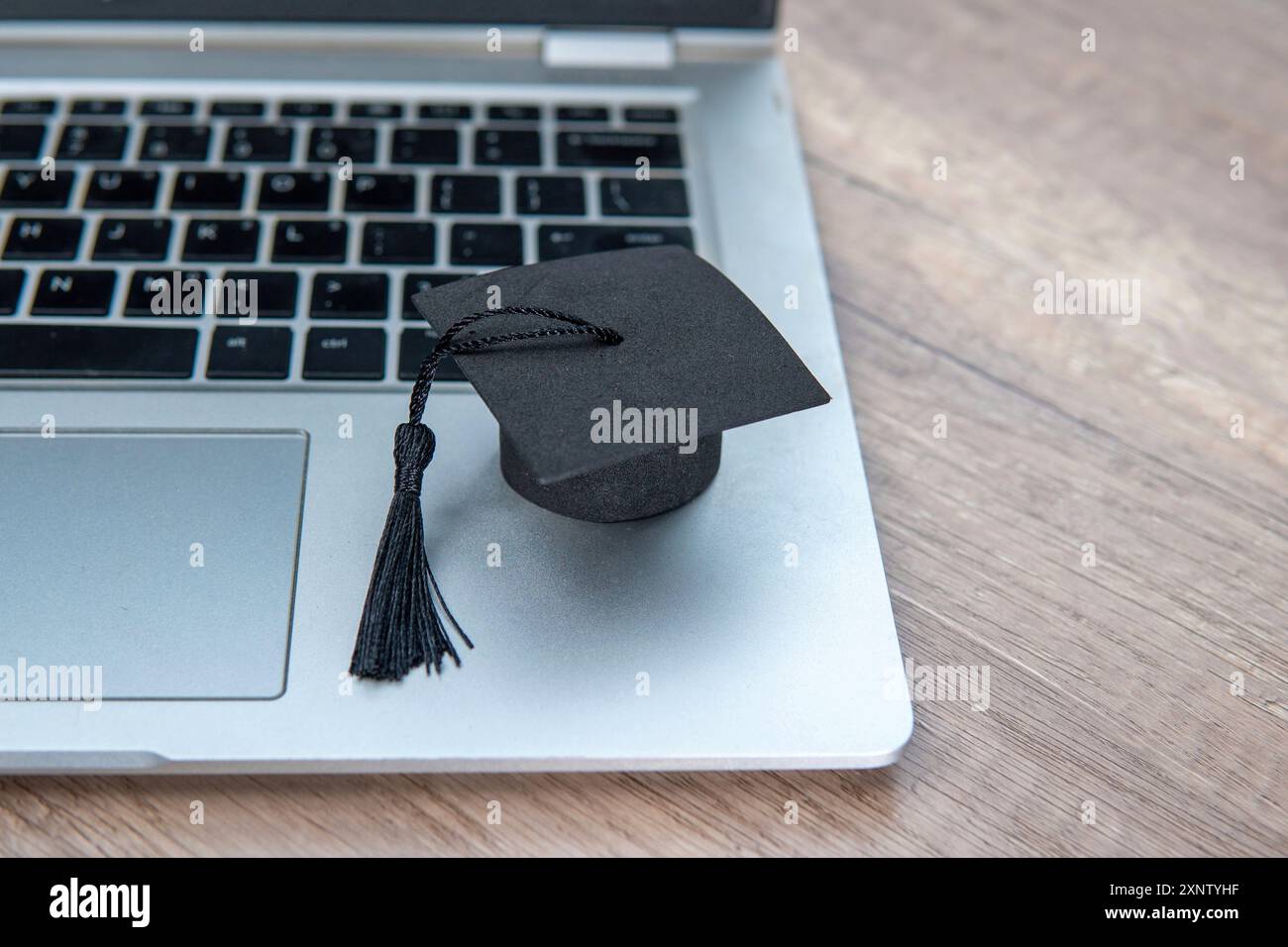 Un berretto graduato e un notebook. Copia spazio per il testo. Apprendimento online e concetto di risultati accademici. Foto Stock