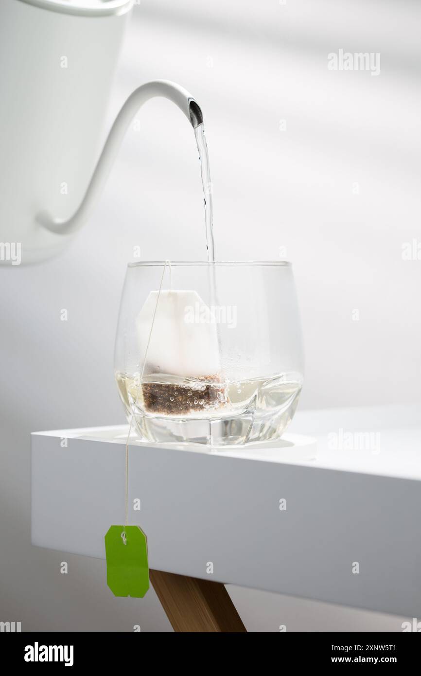 Elegante cascata d'acqua dalla pentola al bicchiere; un momento squisito di preparazione del tè congelato nel tempo. Foto Stock