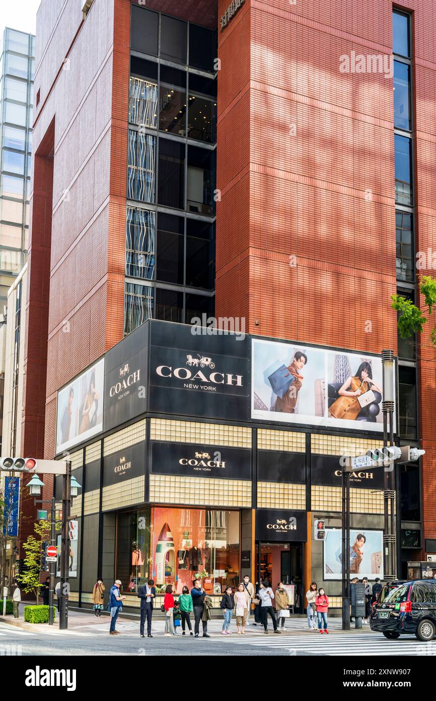L'elegante negozio di pullman in Ginza in via Namiki-dori, persone fuori dal negozio in attesa di utilizzare l'attraversamento pedonale di fronte. Verticale. Foto Stock