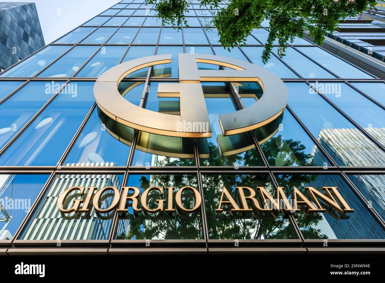 Il logo e il marchio Giorgio Armani svettano sullo spettatore sulla facciata in vetro riflettente del suo negozio Ginza a Tokyo. Foto Stock