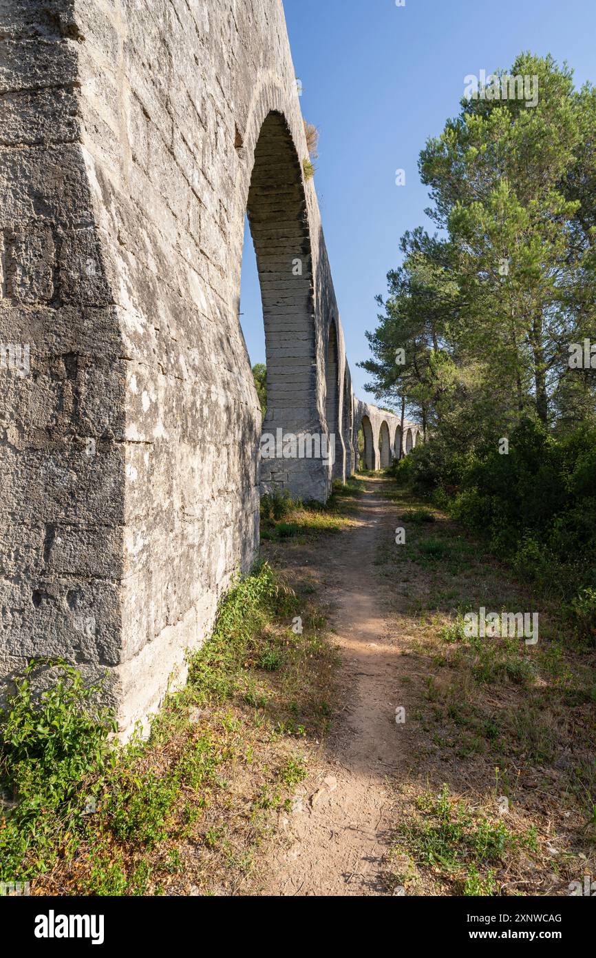 Vista panoramica verticale dell'antico acquedotto in pietra, famoso monumento storico di Castries, Herault, Francia Foto Stock