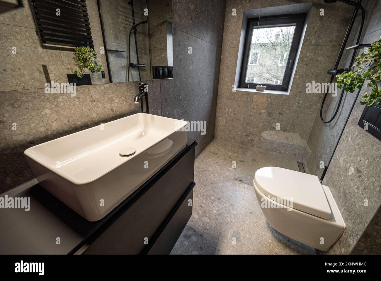 Interni di un bagno moderno con eleganti pareti piastrellate e pavimento in cemento. Interno di un bagno moderno con pareti piastrellate e cemento. Moderno Foto Stock