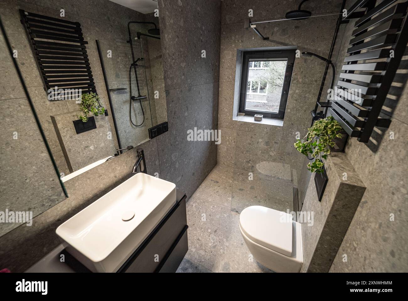 Interni di un bagno moderno con eleganti pareti piastrellate e pavimento in cemento. Interno di un bagno moderno con pareti piastrellate e cemento. Moderno Foto Stock