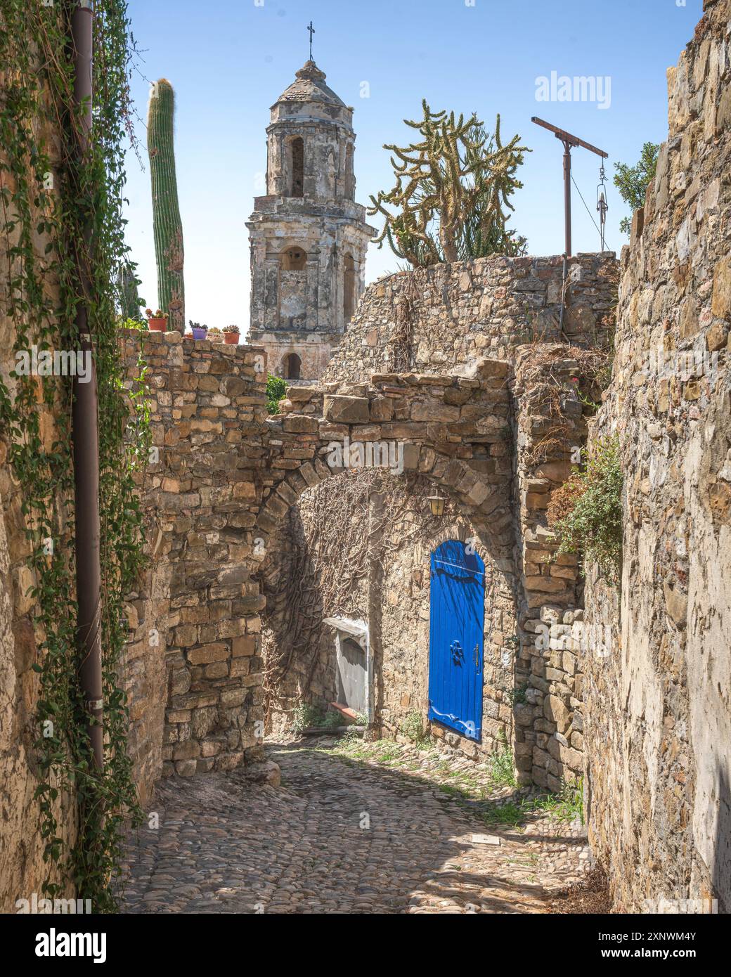 Porta blu e vista del campanile in una strada di Bussana Vecchia. Città fantasma a Sanremo, Liguria, Italia. Abbandonato a causa di un terremoto nel 1887, to Foto Stock