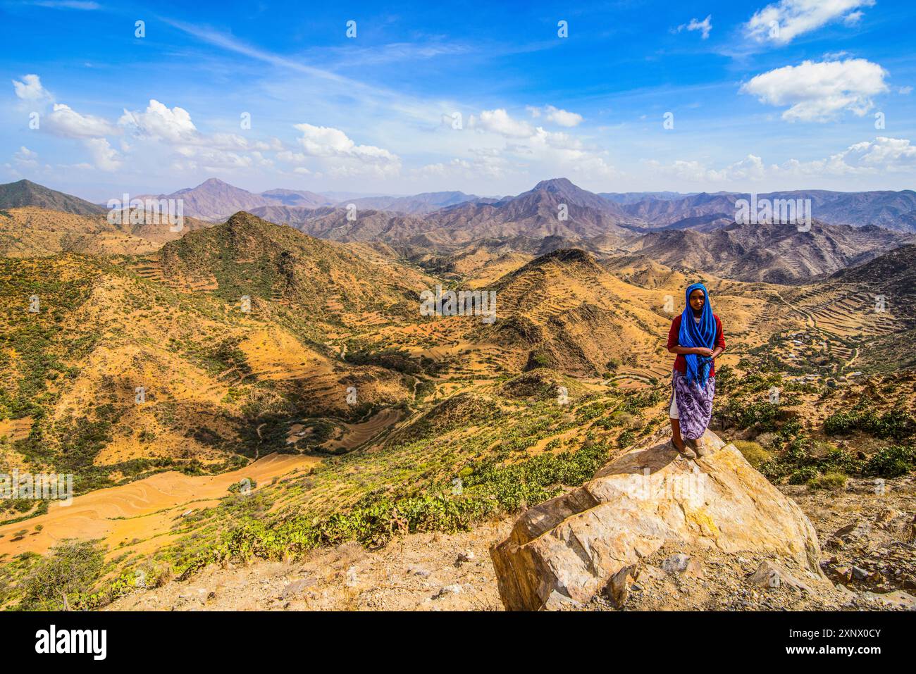 Donna del posto in piedi su una roccia in uno splendido scenario di montagna lungo la strada da Massawa ad Asmara, Eritrea, Africa Foto Stock