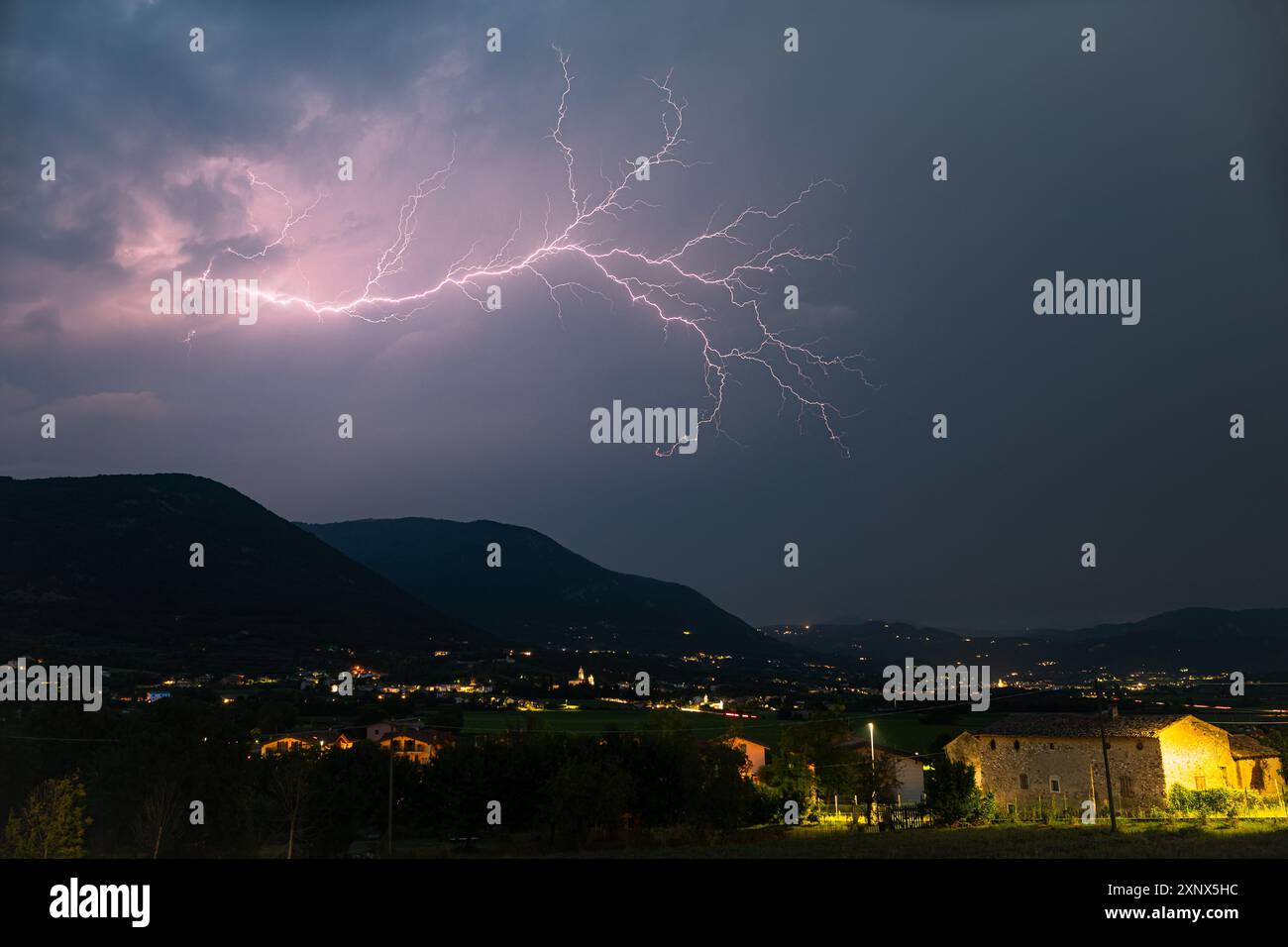 Un fulmine con molte diramazioni laterali apre il cielo sulle montagne delle Alpi italiane Foto Stock