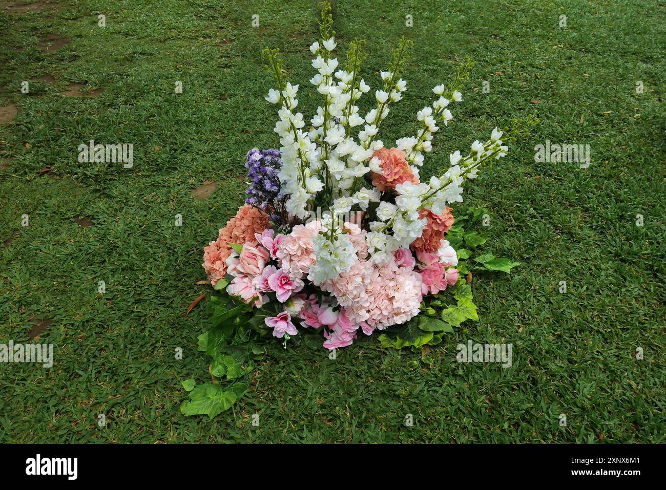 Finti fiori di plastica collocati sul campo verde sono solo per la decorazione temporanea della sede dell'evento Foto Stock