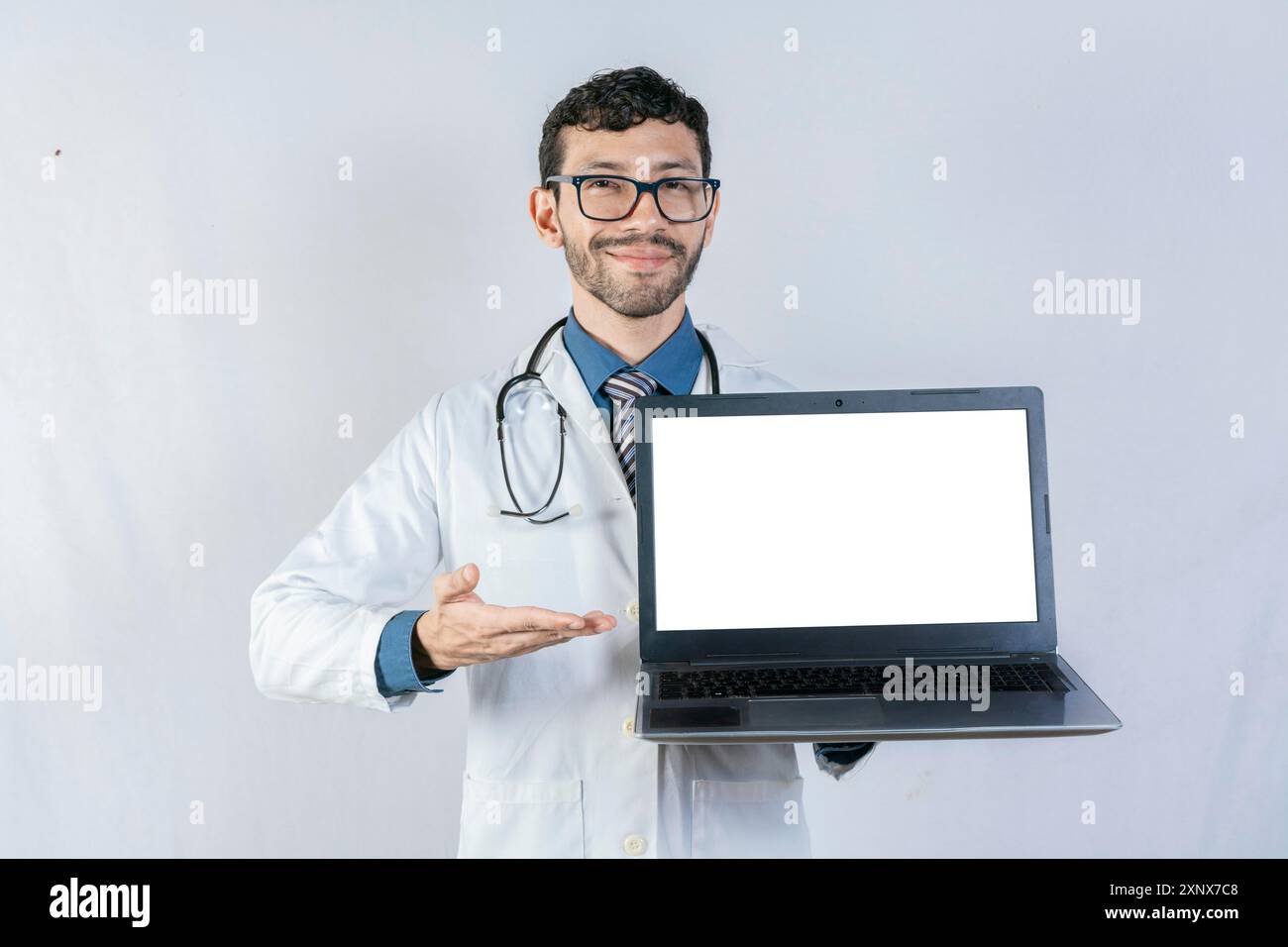 Medico sorridente che mostra lo schermo del notebook isolato. Bel medico che indica lo schermo del computer portatile isolato Foto Stock