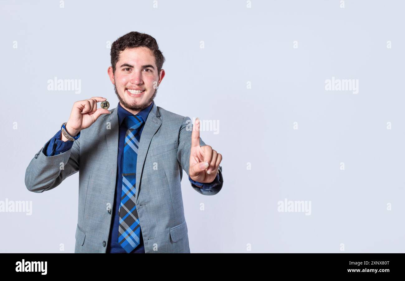 Uomo d'affari che ha un bitcoin isolato. Uomo d'affari sorridente con un bitcoin puntato, uomo d'affari attraente con un bitcoin e. Foto Stock