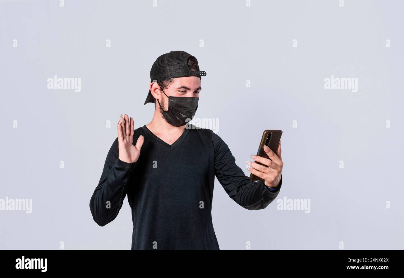 Uomo che fa videochiamata isolato, ragazzo che fa videochiamata con maschera facciale, maschera facciale concetto di videochiamata Foto Stock
