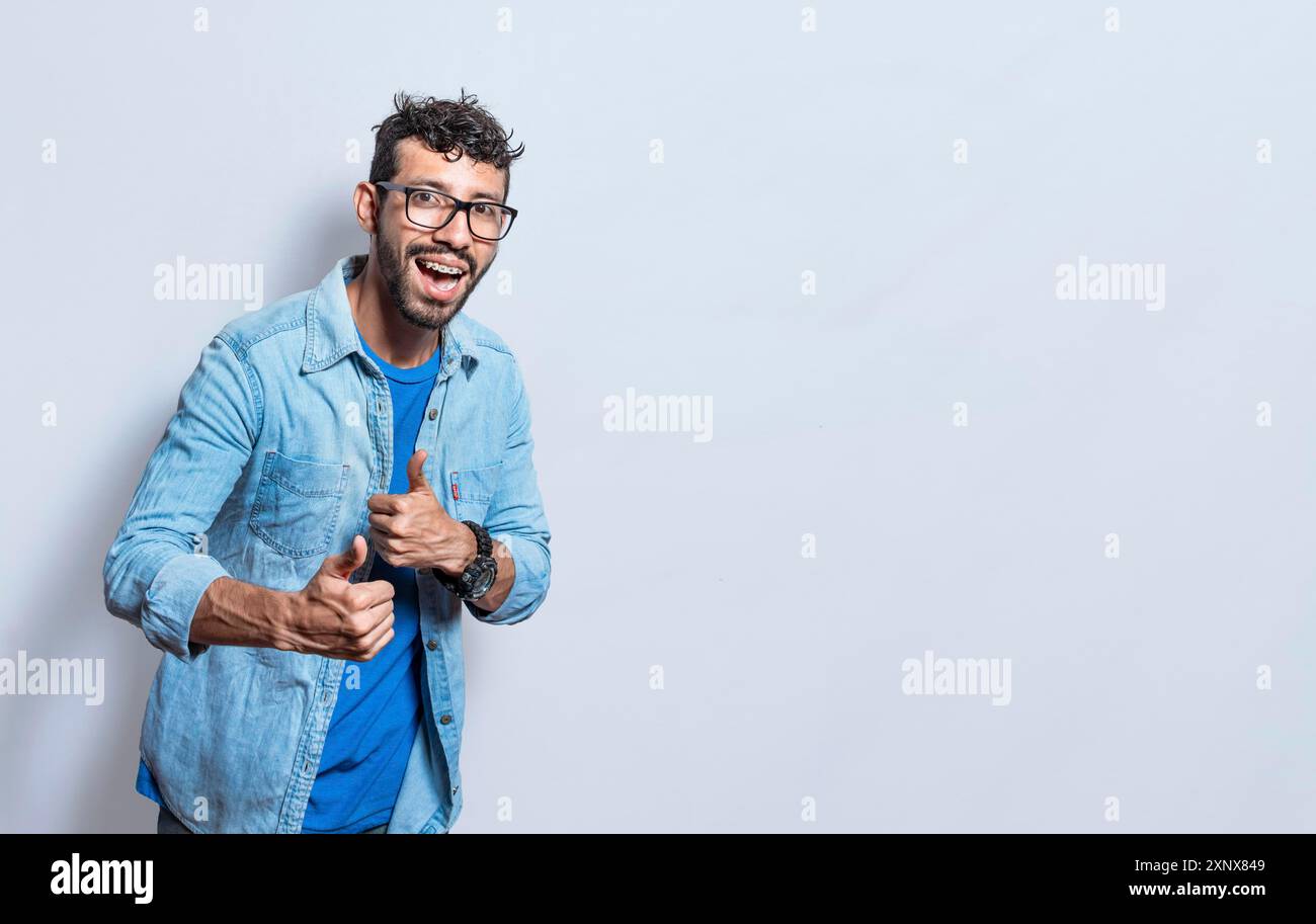 Bell'uomo con i pollici che fanno bene, giovane uomo con i pollici su sfondo bianco, sorridente uomo che mostra un gesto ok guardando la macchina fotografica Foto Stock